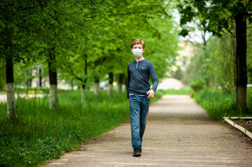 A masked teenager walks briskly down the street alone.