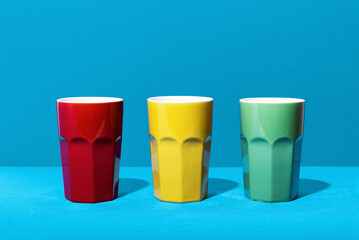 Colorful ceramic mugs on blue background