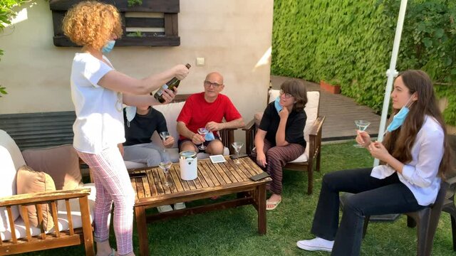 Birthday party in the garden uncorking a bottle of wine. Concept of new normality