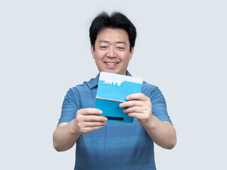 A middle-aged Asian man holding a bank passbook in his hand on a gray background.
