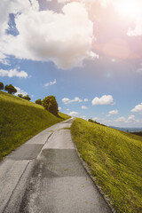 Asphalted steep mountain road on an Austrian mountain. Blue sky and green meadow, summer time