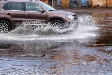 Вriving car on flooded road during flood caused by torrential rains. Cars float on water, flooding...