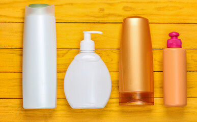 Bottles of shampoos on a yellow wooden background. Cosmetics. Top view