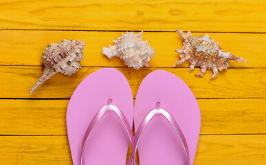 Flip flops with seashells on a yellow wooden background. The concept of a beach holiday, resort. Top view