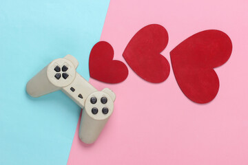 Game lover. Retro gamepad with red hearts on pink blue pastel background. Retro 80s. Top view.