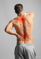 Man suffering from pain in neck and lower back on light grey background