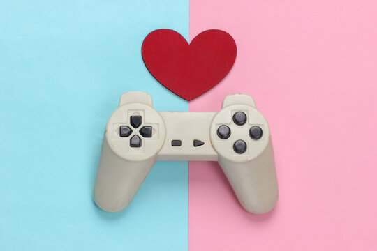 Game lover. Retro gamepad with red heart on pink blue pastel background. Retro 80s. Top view.
