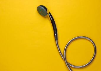 Shower head hose on yellow background. Top view