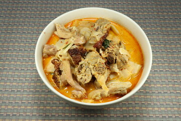 Spicy cutting bamboo shoot with chopped chicken thigh, basil, chilly, curry paste and coconut milk in the bowl. Traditional hot and spicy soup menu serving with rice noodle. Local food concept. 