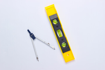 Construction level and compass on white studio background. Top view. Minimalism