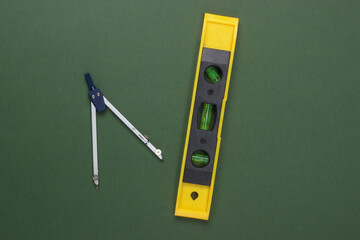 Construction level and compass on green studio background. Top view. Minimalism
