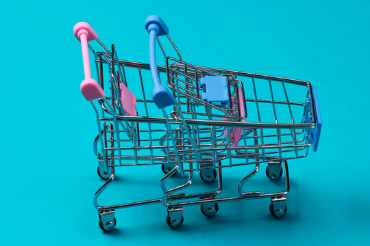 Two mini supermarket trolleys on blue background. Shopping concept.