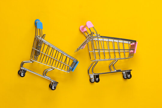 Two mini supermarket trolleys on yellow background. Shopping concept. Top view