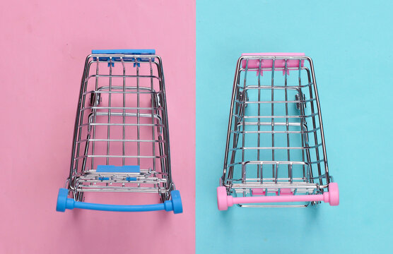 Two mini supermarket trolleys on blue pink pastel background. Shopping concept. Top view. Minimalism