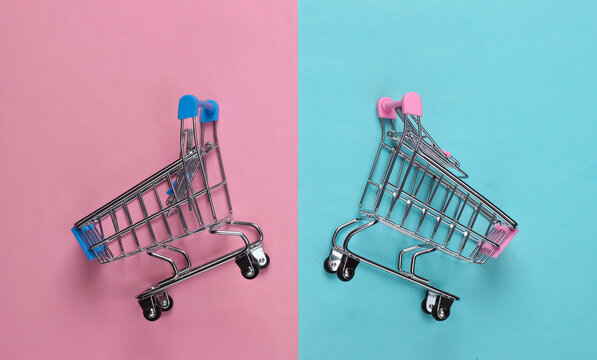 Two mini supermarket trolleys on blue pink pastel background. Shopping concept. Top view. Minimalism