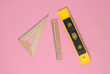 Engineering construction supplies on a pink pastel background. Construction level, rulers. Top view