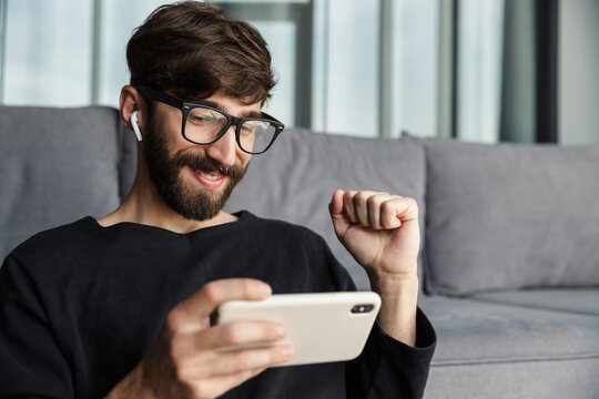 Image of excited man using cellphone and making winner gesture