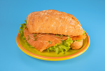 sandwich with salmon and salad on blue background