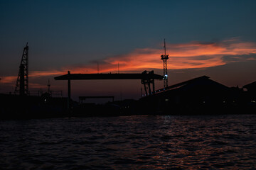 Fototapeta premium Sunrise or sunset view of Chao Phraya River , Bangkok, Thailand . Shows water transport. reflective of the sun. Image contain certain grain or noise and soft focus.