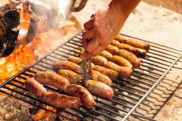 Sausages on the grill are cooked on the grill of an open fire. Grilled meat on hot coals. Barbecue