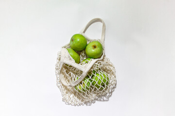 Fresh apples in a string bag, eco-friendly product on a light  background. No plastic, only natural materials and natural products. Concept of life without plastic.