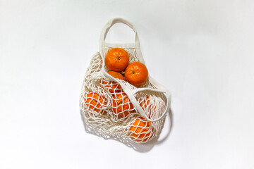 Fresh mandarines in a string bag, eco-friendly product on a light  background. No plastic, only natural materials and natural products. Concept of life without plastic.