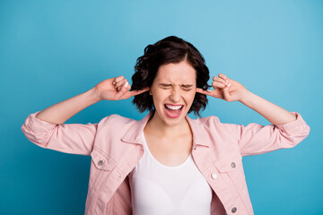 Photo of beautiful crazy lady short hairdo hold fingers into ears yelling loudly can't stand terrible noise sound causing migraine wear casual pink jacket isolated blue color background