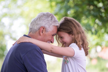 Grandfather and  Granddaughter  face-to-face outdoors together.