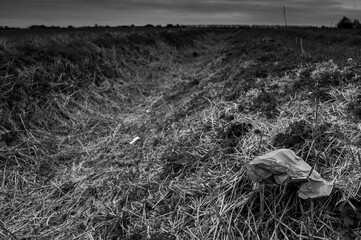 Discarded rubbish waste garbage by a roadside in black and white