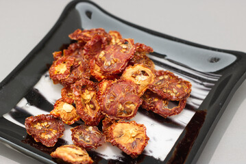 Red sun dried Tomatoes on a white and black glass plate  