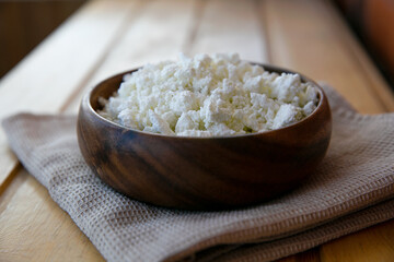cottage cheese on wooden plate on a brown towel and a wooden table