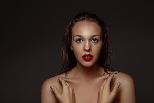 Natural purity. Portrait of beautiful stylish woman isolated on dark studio background. Caucasian model with red lipstick, wet hair and shiny skin, bright make up. Beauty, fashion, emotions concept.