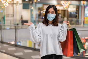 woman wearing medical mask while shopping with bag at mall for prevention from coronavirus...