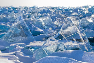 Luminous transparent triangle blue ice blocks among field of  broken ice, beautiful winter landscape or background
