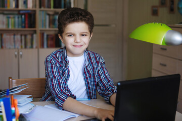 Teenager boy sitting at a table with a laptop.