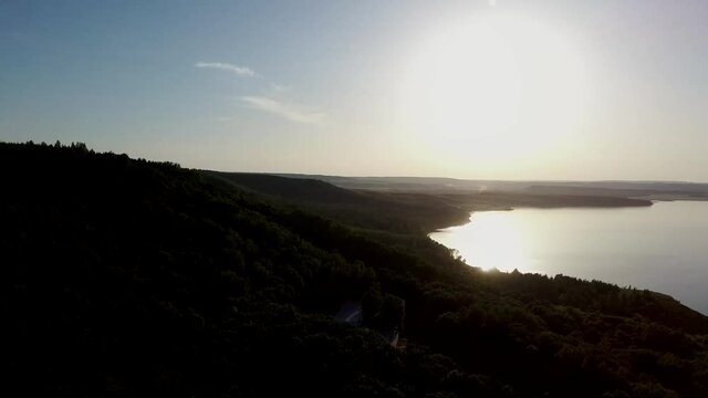 Aerial video of a lake in the mountains at sunset on a sunny summer warm day. Morning or evening in the mountains