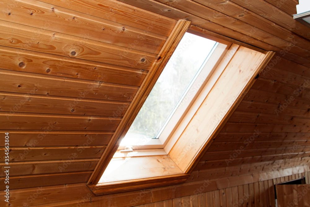 Poster open dormer window in wooden house in the attic. room has sloping ceiling made of natural eco-materi