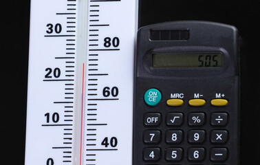 Global warming concept. Climate control. Weather thermometer and calculator on black background. Top view.
