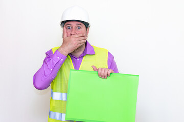 Portrait of curious surprised architect in a construction helmet holding a folder, free place mock up banner advertisement.Studio shoot.