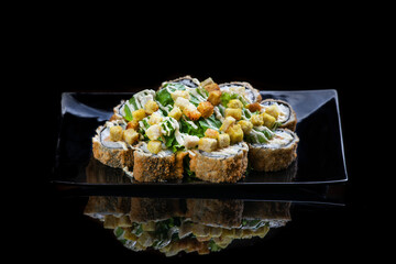 A close up of food fried sushi rolls isolated on black. reflection