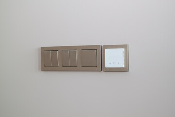 Close up view of electric light switches and sensor for floor heating on an empty wall