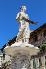 Włochy. Fontanna Madonna Verona i wieża Torre dei Lamberti w Weronie. Niebieskie niebo. Rzeźba. © Anastasiia
