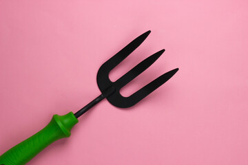 Mini garden fork on a pink studio background. Top view