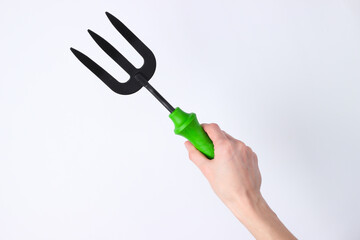 Hand holding mini garden fork isolated on white studio background.