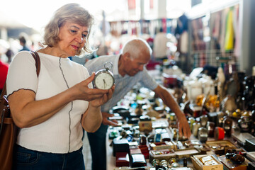Loving mature couple buys alarm clock on flea market