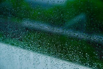 Water drops after the cloudburst on the window. Green background.