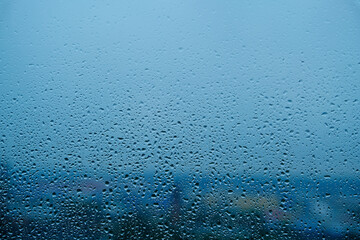 Water drops after the cloudburst on the window. Blue background.