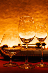 Set of empty glasses for different drinks, warm orange tinted. Empty wine glass, cognac glass and liquor glass
