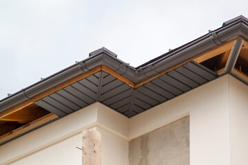 close-up view of a house with a gray roof and plums and filing of roof overhangs with soffits of...