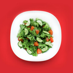 Fresh salad with tomatoes, 
cucumber, salad leafs, lettuce on red  background top view. 
Food in a white bowl. Healthy food. Minimalism concept.